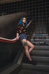 Canvas Print - Attractive and beautiful woman with blue hair leaning on the escalator