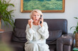 © Albina - An elegant woman looks in surprise at the phone while sitting on a sofa in her house.