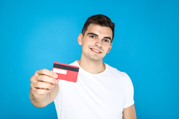 Canvas Print - Young man showing credit card on blue background