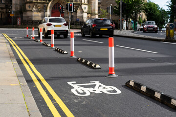 Bike lane. Sign for bicycle painted on the asphalt. Car and traffic in background. Cycle path.