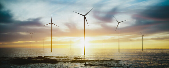 Wall Mural - wind turbines spinning at sunset over the sea