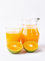 Wall Mural - Jug, glass of orange juice and orange fruits with green leaves  on white background