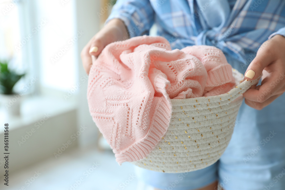 Woman holding wicker basket with plaid in room