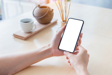 cell phone mockup image blank white screen.woman hand holding texting using mobile on desk at coffee shop.background empty space for advertise.work people contact marketing business,technology