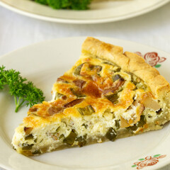 Wall Mural - Piece of quiche with chanterelles, herbs and cheese on a white plate