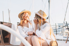 Two Beautiful Blonde Girls Friends Mother And Daughter In White And Straw Hats On The Yacht At The Pier