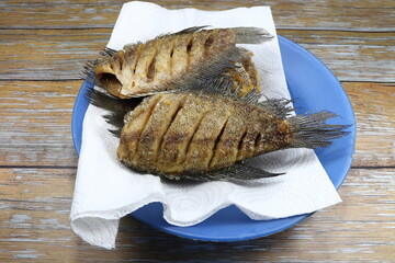 Deep fried Gourami fish (Snakeskin fish) on the plastic plate. Traditional crispy and crunchy fish in Asia. Famous side dish with porridge. 