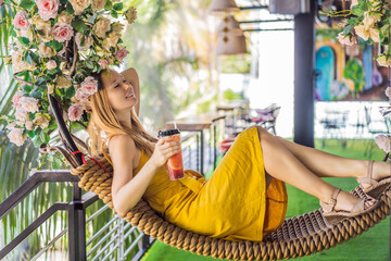 Young woman drinks summer fruit drink on a summer terrace