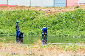 two african men cleaning up a polluted river in cape town, south africa concept environmental care a