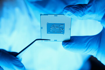 Close-up of professional developer. Testing computer technology. Microelectronics design. Macro shot of smart male engineer holding electronic component with tweezers. Repair and maintenance concept