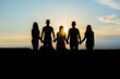 © Довидович Михаил - Cohesion concept. Black silhouettes of friends holding hands stands at sunset.