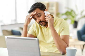 technology, communication and remote job concept - indian man calling on smartphone with laptop comp