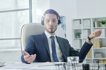 Poster - Young service support operator talking to customer using hands-free device in modern office