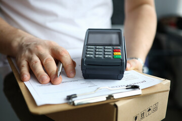 Close-up of delivery service and adult with cashier machine for payment. Nfc technology counter. Person with clipboard for sign and package. Client make transaction pay bill on terminal