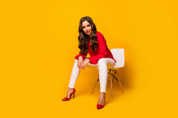 Poster - Full length photo of attractive chic business lady sit bossy comfy chair flirty mood look side empty space wear red shirt white trousers high-heels isolated yellow vivid color background