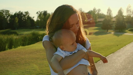 Wall Mural - Woman holding boy on hands in park. Beautiful mother hugging son in meadow