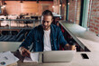 © LIGHTFIELD STUDIOS - cheerful businessman looking at notebook and holding paper cup near smartphone with blank screen and laptop