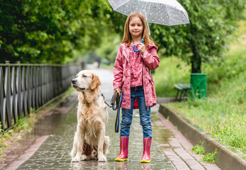 Little girl walking dog in rainy park