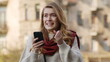 © stockbusters - Cheerful woman jumping with phone. Excited girl looking cellphone on street.