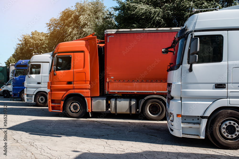 Foto Lateral View Of Trucks Staying In The Truck Parking On The Sunset foto-lateral-view-of-trucks-staying-in-the-truck-parking-on-the-sunset