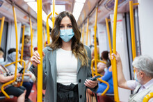 Enterprising Young Woman Wearing A Face Mask Travelling On Public Transport During Rush Hour. Selective Focus. New Normal Concept.