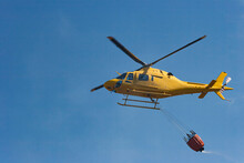 A Fire Helicopter Carries Water To Put Out A Fire That Has Been Caused By The Heat Of The Summer.