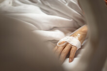 Close Up Hand Of Young Peripheral Venous Catheter In The Hand For Intravenous Medication During Lying In The Hospital Bed.  