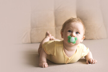 Wall Mural - baby lying on the sofa with his pacifier. Soft focus, copy space.