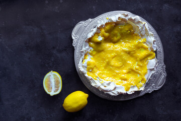 Wall Mural - Homemade meringue basis for cake Pavlova with lemon curd. Crusty dessert on the black background