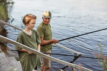 Wall Mural - Father and son fishing on wooden stairs leading to water,, grandfather teaching his grandson to catching fish, family spending weekend together near lake.