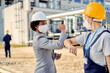 © Drazen - African American civil engineer and worker wearing face masks while elbow bumping at construction site.