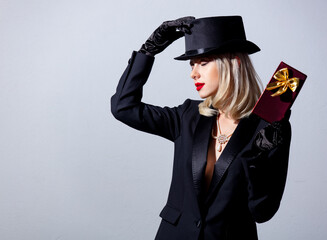 Poster - Blonde woman in black jacket and top hat with gift box on white background