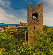An Isolated Tower Rises Above The Foliage Before The Tower Bridge And Fortress At Spoleto, Italy In Summer