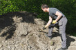 © oleksandr - A man working with a shovel near a heap of soil.