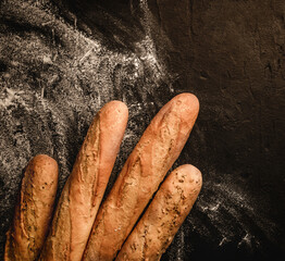 Wall Mural - Freshly bread baguettes on black slate background with flour. Pastries and bakery, Food concept, top view