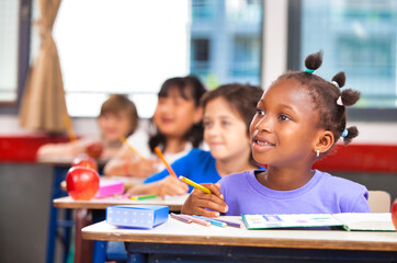 Elementary school scene. African schoolgirl with multi ethnic classmates in the classroom