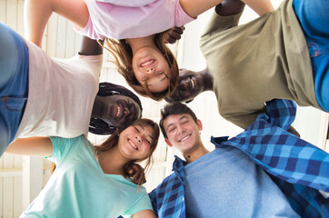 Wall Mural - Happy group of multi ethnic teenagers outdoor together looking downward to the camera