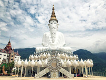 White Buddha Statue And Cloud Background At Wat Prathat Phasornkaew Thailand