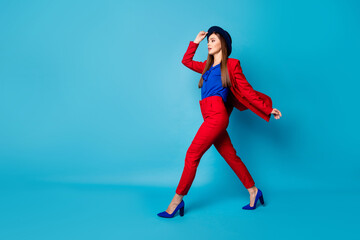 Wall Mural - Full body profile photo of self-confident pretty business lady boss walking down street wear retro cap red suit blouse blazer pants high-heels isolated blue color background