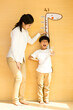 Young mother measuring height for son at home