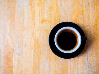 Hot black intense Americano coffee in a black coffee cup with handle placed on a wooden table.