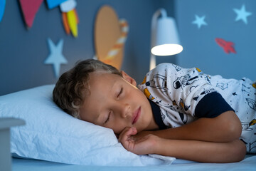 Cute little boy sleeping in his galaxy bedroom