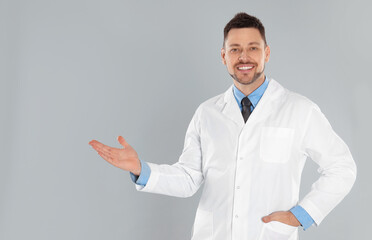 Wall Mural - Happy man in lab coat on light grey background