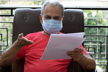 Senior Man Wearing Protective Face Mask Worried About Financial Bills At Home During Lockdown