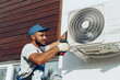 © fotofabrika - Repairman in uniform installing the outside unit of air conditioner