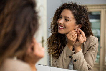 Businesswoman is  putting earrings while preparing for work.