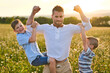 © Louis-Photo - happy family of father and two childs on field at the sunset having fun