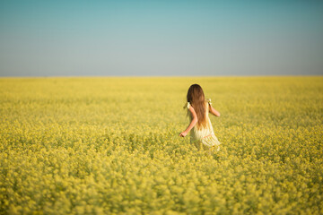 Wall Mural - portrait of a teenage girl in a yellow dress running across the field in summer