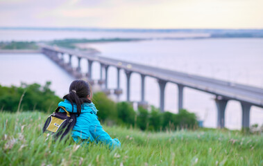 girl sitting on the mountain. The woman is looking at the bridge. Peaceful landscape. Traveler's vacation