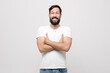 © Yuliya - Studio portrait of surprised pretty young man with short haircut standing over white background, looking puzzled to camera with crossed arms on his chest